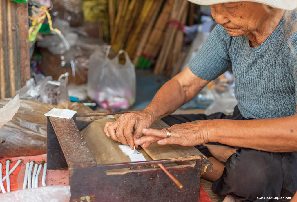 Une vieille femme roule des cigarettes et l'apprend aux enfants à Battambang-Cambodge